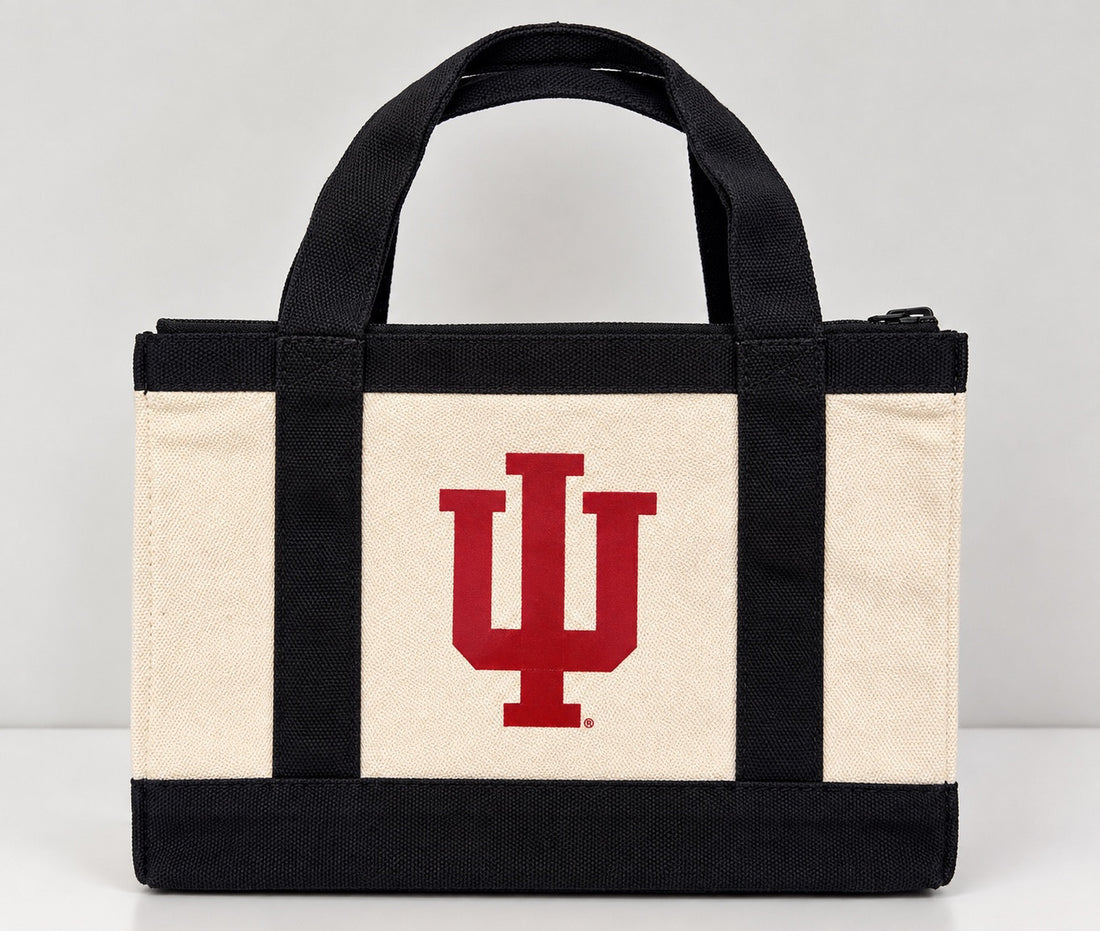 Cream-and-black tote with a red IU logo, two carry handles, and a zip closure